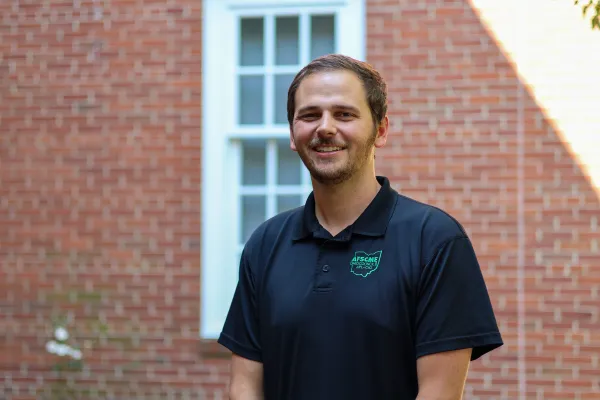 Photo of a white man with short brown hair in black polo with AFSCME Ohio Council 8 logo on the chest against brick building backdrop.
