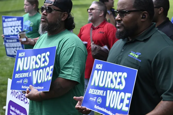 Photo of people standing at the rally for nurses organizing at Nationwide Children's Hospital holding signs that say "Nurses deserva a voice"